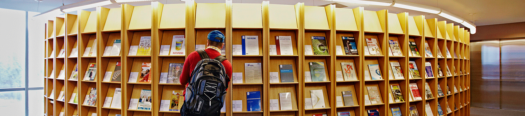 This is a picture of a student browsing at a magazine rack in one of YorkU's libraries.