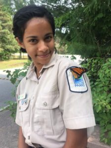 Aliya in her Ontario Parks uniform with a Monarch butterfly